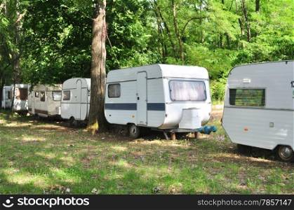 outdoor forest trailer camp caravan cars behind trees