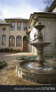 Outdoor front view of affluent home with fountain.