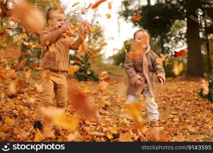 Outdoor fun in autumn. Children playing with autumn fallen leaves in park. Happy little friends. Outdoor fun in autumn. Children playing with autumn fallen leaves in park. Happy little friends.