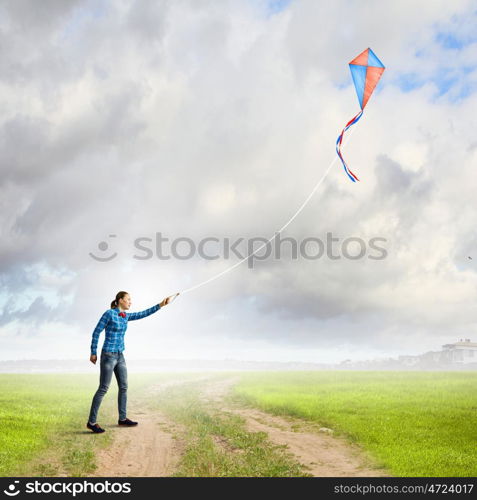 Outdoor game. Young woman in casual playing with colorful kite