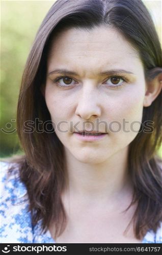 Outdoor Head And Shoulder Portrait Of Worried Young Woman