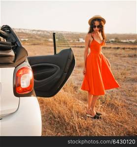 Outdoor lifestyle photo of beautiful stylish woman at car cabriolet. Holiday and travel. Summer trip. Freedom, youth and carefree