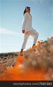 Outdoor lifestyle photo of beautiful young woman in white suit the poppy field. Freedom and independence