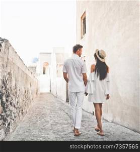 Outdoor lifestyle photo of happy young couple in white european town. Walking on Santorini island