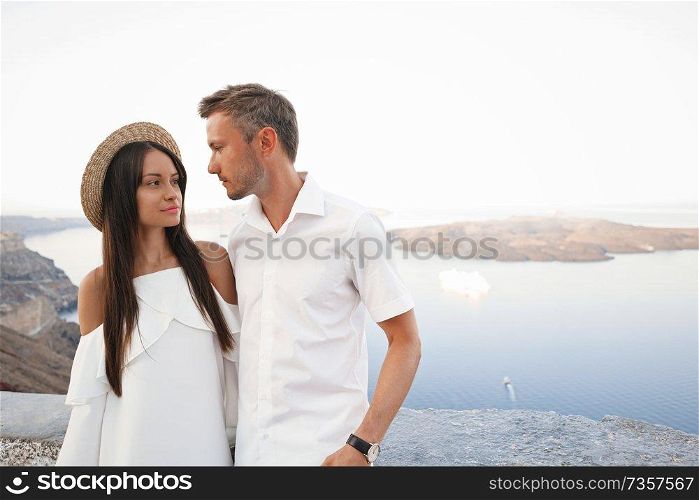 Outdoor lifestyle photo of happy young couple in white european town. Walking on Santorini island
