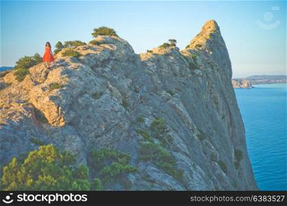 Outdoor lifestyle photo of woman in red dress walking on rock. Travel background. Tourism.