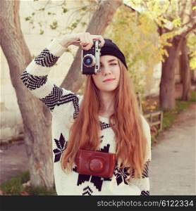 Outdoor lifestyle portrait of pretty young hipster woman making photo. Retro photographer. Modern urban girl has fun with vintage photo camera.