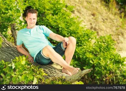 Outdoor nature relaxation concept. Handsome man spending his free time outside during summertime. Man spending free time outside, looking at nature