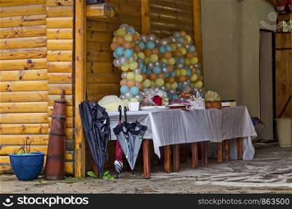 Outdoor party in Rila Park decorated with colorful balloons, cake and gifts on a rainy day near Dupnitsa, Bulgaria