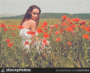 Outdoor photo of beautiful young woman in the poppy field
