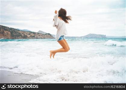 Outdoor photo of beautiful young woman jumping at the sea