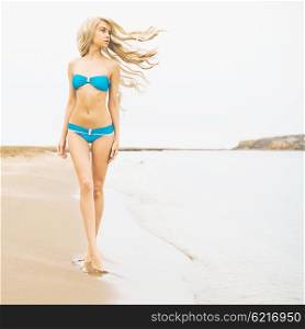Outdoor photo of beautiful young woman walking at the sea