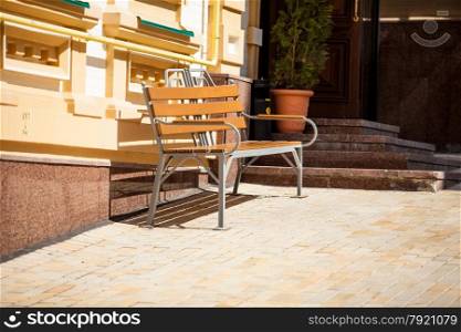 Outdoor photo of bench on street at sunny day