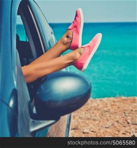 Outdoor photo of female legs from the window of car. Freedom, summer travel and road trip