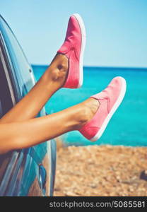 Outdoor photo of female legs from the window of car. Freedom, summer travel and road trip