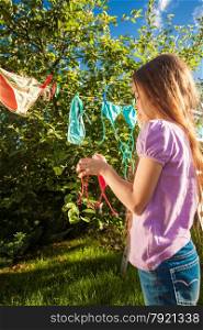 Outdoor photo of young girl drying clothes on clothesline