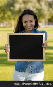 Outdoor portrait of a beautiful African American holding a shalkboard