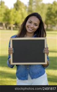 Outdoor portrait of a beautiful African American holding a shalkboard 