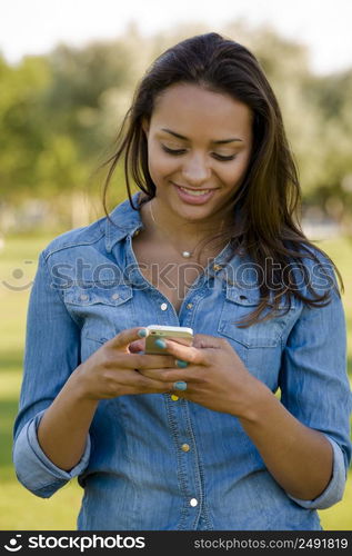 Outdoor portrait of a beautiful African American sending a sms