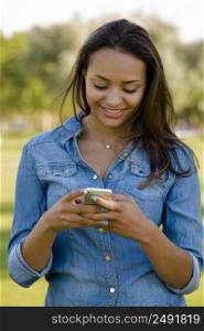 Outdoor portrait of a beautiful African American sending a sms