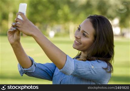 Outdoor portrait of a beautiful African American taking a photo with the cellphone