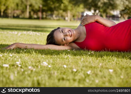 Outdoor portrait of a beautiful African American woman lying on the grass