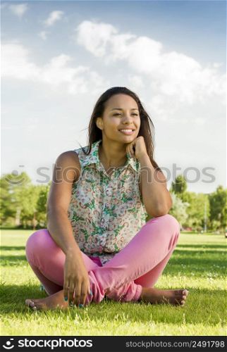 Outdoor portrait of a beautiful African American woman sitting onn the grass