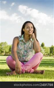 Outdoor portrait of a beautiful African American woman sitting onn the grass
