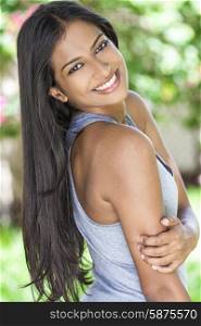 Outdoor portrait of a beautiful Indian Asian young woman or girl outside in summer sunshine with perfect teeth and long hair