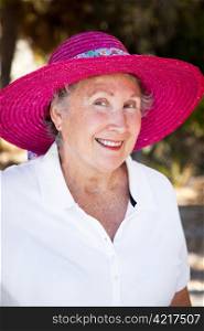 Outdoor portrait of a beautiful senior woman in a pink sun hat.