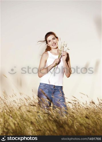 Outdoor portrait of a beautiful woman holding flowers on a summer day