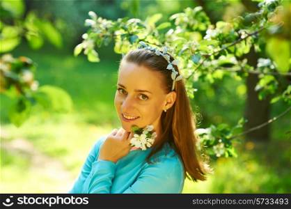 Outdoor portrait of a beautiful woman in dress among apple blossoms