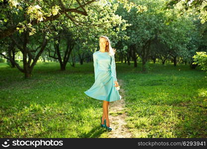 Outdoor portrait of a beautiful woman in dress among apple blossoms