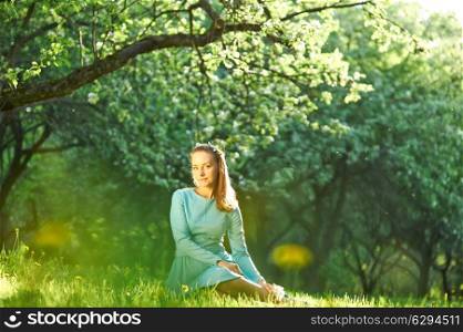 Outdoor portrait of a beautiful woman in dress among apple blossoms