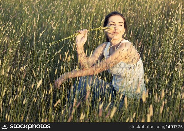 Outdoor portrait of a beautiful woman smelling flowers on a summer day