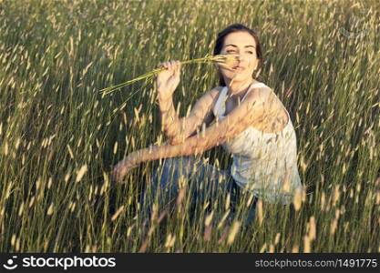 Outdoor portrait of a beautiful woman smelling flowers on a summer day