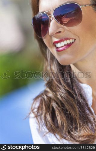 Outdoor portrait of a beautiful young brunette woman in her thirties wearing aviator style sunglasses