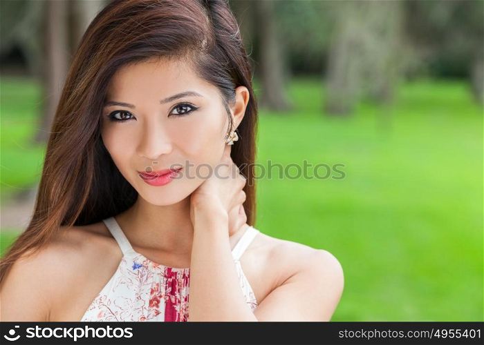 Outdoor portrait of a beautiful young Chinese Asian young woman or girl in a natural green woodland setting