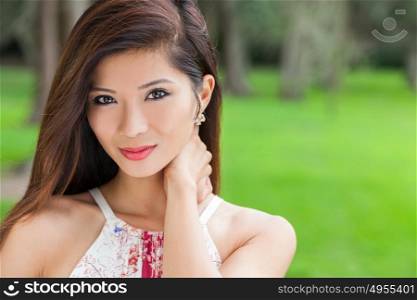 Outdoor portrait of a beautiful young Chinese Asian young woman or girl in a natural green woodland setting