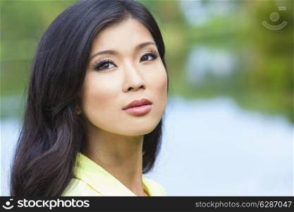 Outdoor portrait of a beautiful young Chinese Asian young woman or girl by a lake with reflections