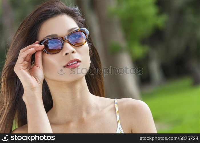 Outdoor portrait of a beautiful young Chinese Asian young woman or girl wearing sunglasses