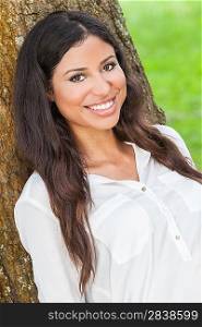 Outdoor portrait of a beautiful young Latina Hispanic woman smiling leaning against a tree