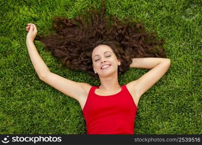 Outdoor portrait of a beautiful young woman lying on the grass