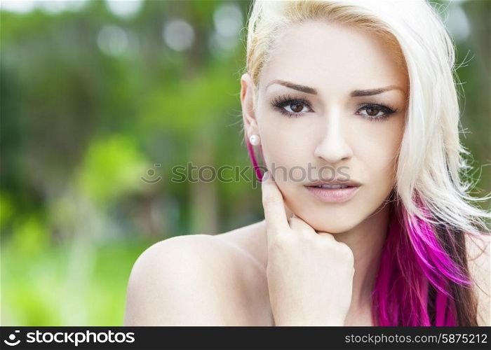 Outdoor portrait of a beautiful young woman or girl with brown eyes, blond and magenta pink hair