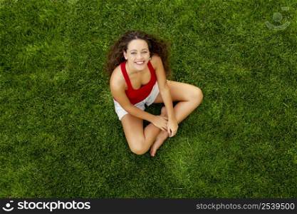 Outdoor portrait of a beautiful young woman sitting on the grass