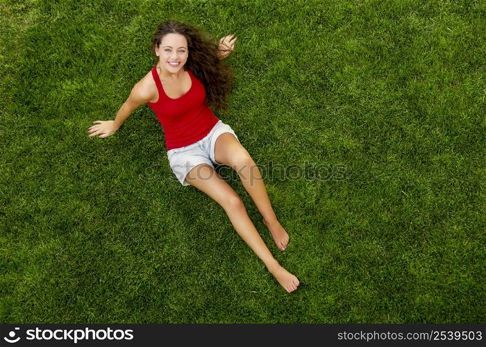 Outdoor portrait of a beautiful young woman sitting on the grass