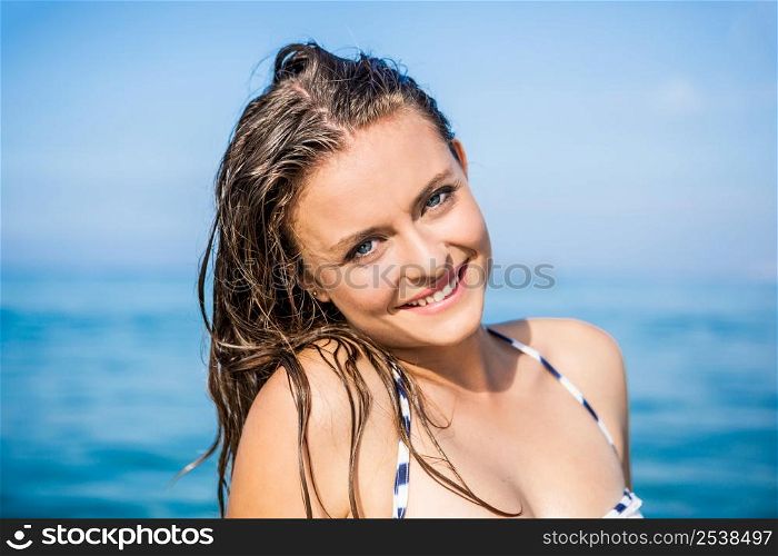 Outdoor portrait of a beautiful young woman with the ocean in the back