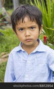Outdoor portrait of Asian Thai little boy serious
