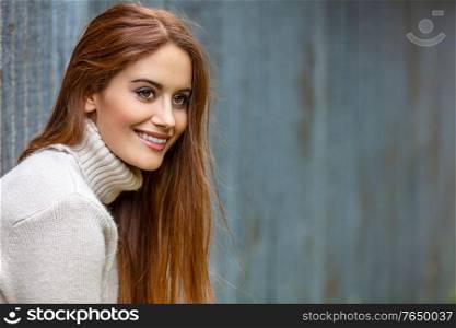 Outdoor portrait of beautiful girl or young woman with red hair smiling and happy in an urban city setting
