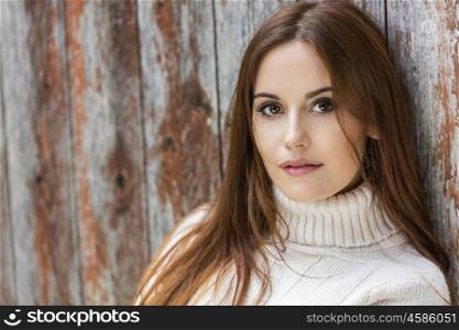 Outdoor portrait of beautiful girl or young woman with red hair wearing a white jumper